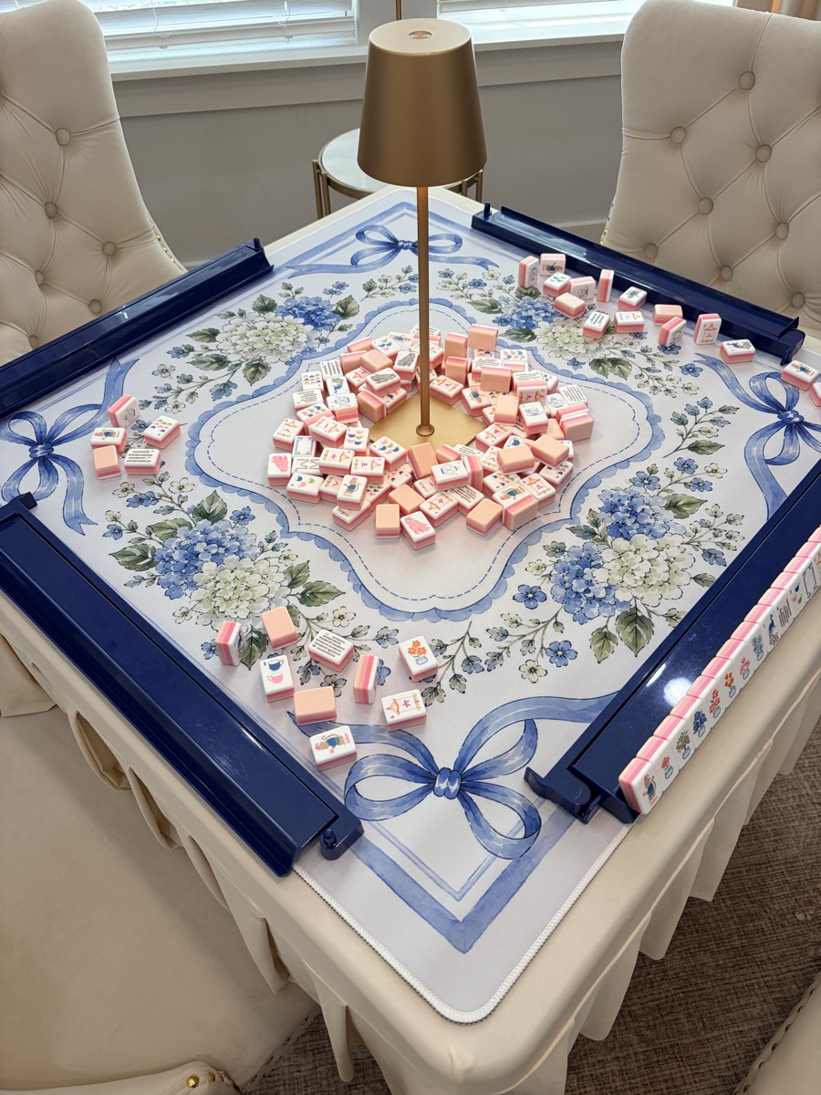 Blush tiles on a blue hydrangea mat with navy racks, set up on a table with a gold lamp