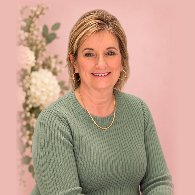 Paula, smiling, in a sage green sweater