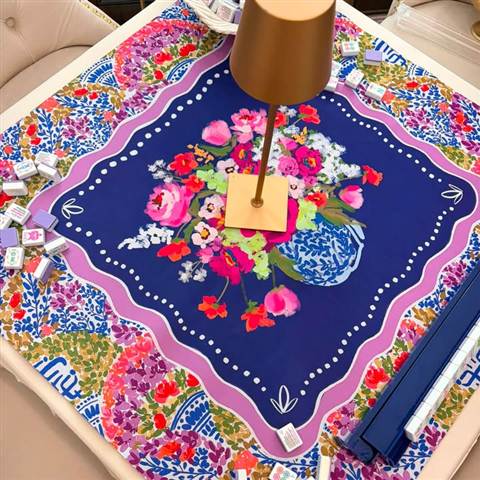 Navy floral mahjong mat with a gold lamp on a skirted table